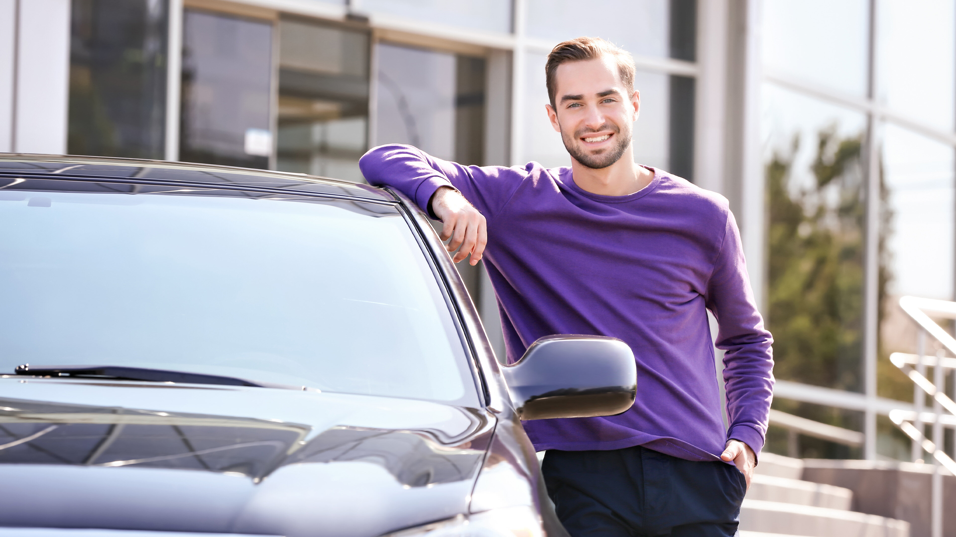Jeune homme accoudé sur le toit d'une voiture